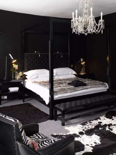 a luxurious bedroom with black walls, a glam chandelier, animal skin rugs and leather furniture just makes drop a jaw