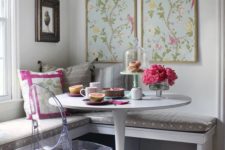 21 a wall-mounted corner bench with a cushion on top, an acrylic chair and floral artworks for a cheery breakfast nook