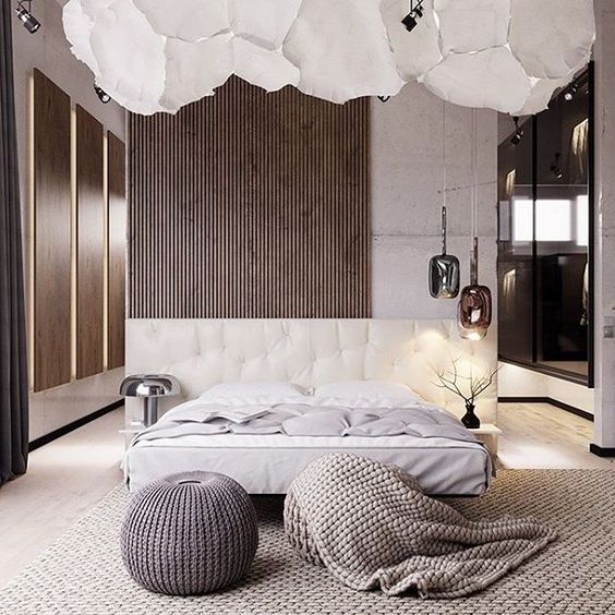 a concrete and wood slat wall, an upholstered refined creamy bed and knit items make the bedroom very inviting