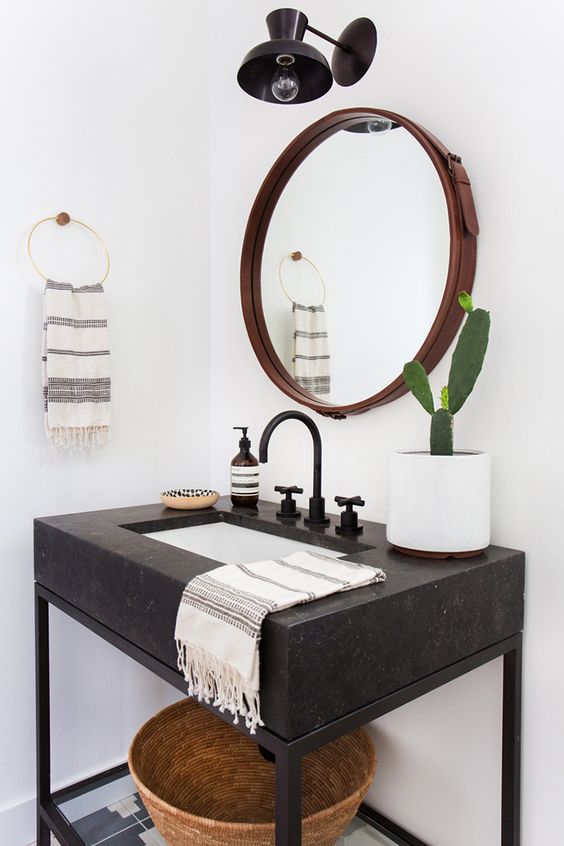 a dark stone vanity with black framing and a glass shelf makes the piece look cool