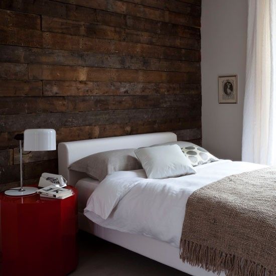 a dark reclaimed wooden wall adds a bold touch and texture to the modern bedroom