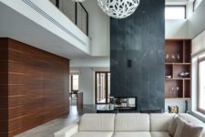 23 a saturated wooden wall and a black stone fireplace wall define this modern space