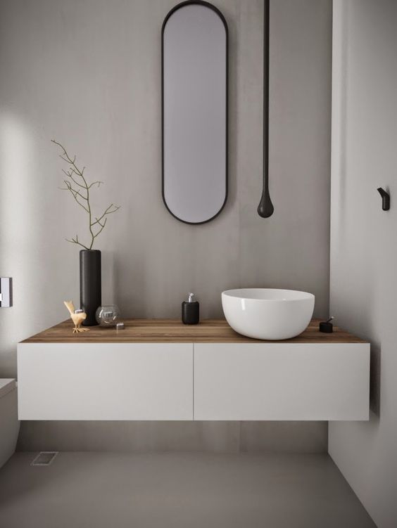 a minimalist white vanity with a light-colored wooden top and a bowl sink