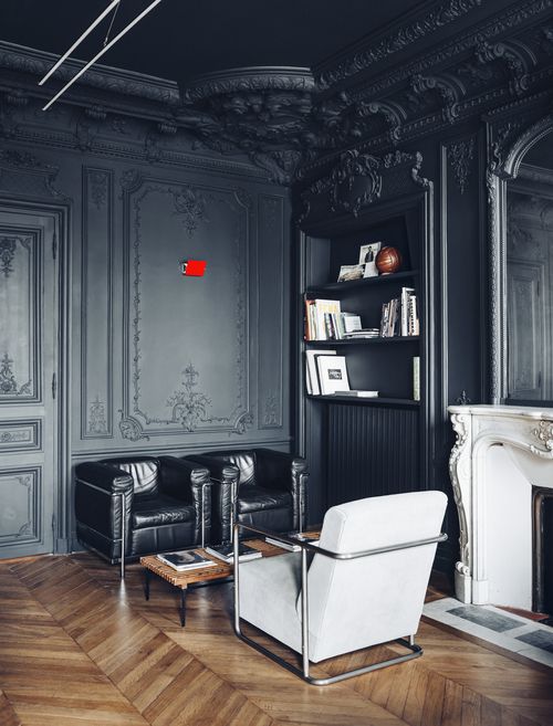 a refined living room with gorgeous black walls and a ceiling with molding and paneling, black and white furniture for a contrasting look