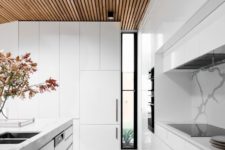 25 a modern white kitchen with sleek cabinets, a wooden ceiling and stone floors