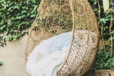 26 a boho-inspired hanging chair with pillows and a blanket in the patio