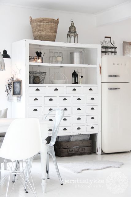 an apothecary cabinet painted white and turned into a comfy cupboard in the kitchen