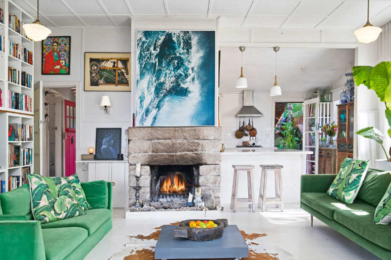 The living room has a strong wow effect, there's a fireplace, emerald velvet sofas and a stunning artwork that depicts the ocean