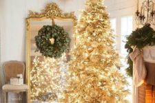 02 a gold pre-lit Christmas tree with white ornaments and a faux fur skirt