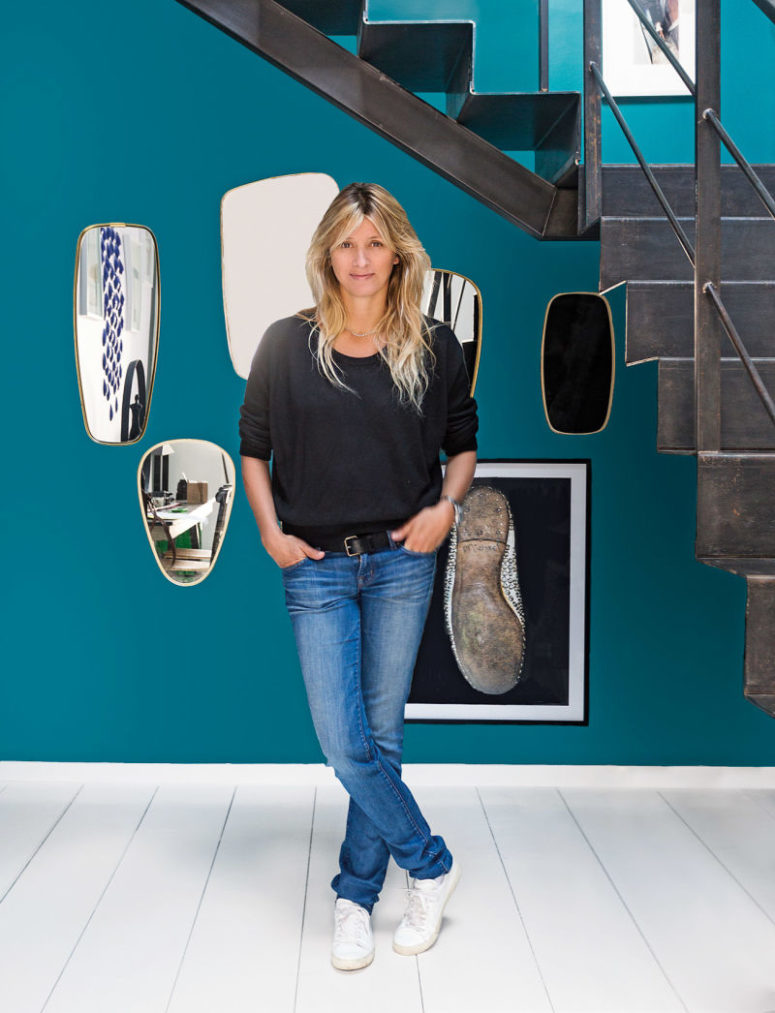 The entryway is done with a turquoise accent wall, mirrors of different shapes and an industrial metal staircase