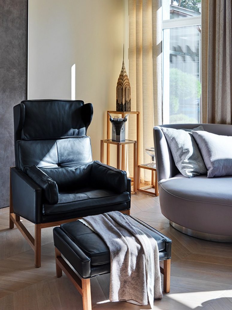 The furniture is comfy, there's a black leather chair with a footrest, a small upholstered sofa