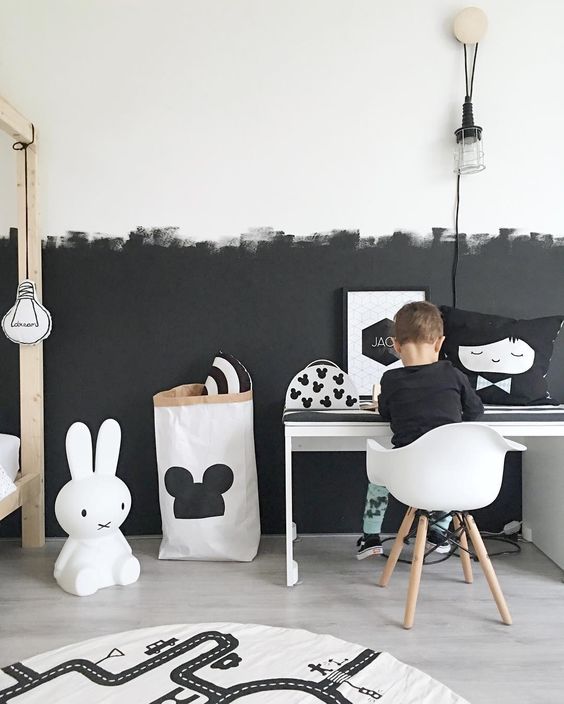 a Scandinavian kid's room with a partly black and partly white wall with a brushstroke pattern