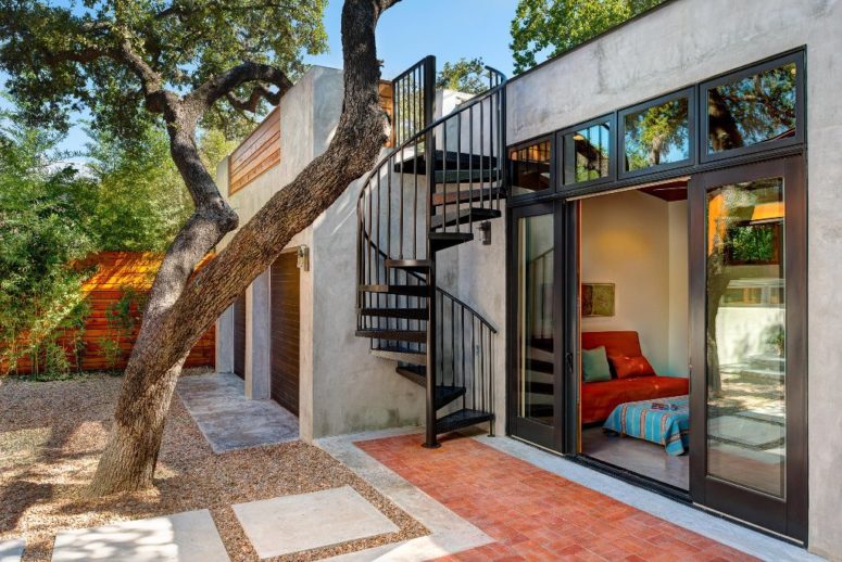 The patio is manicured, its hardscaping and greenery along the fence and a tree bring some shade here, the staircase leads to a rooftop terrace