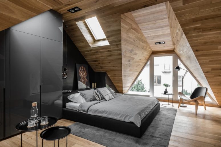 The window with eye-catchy geometry of the ceiling features a reading nook with a comfy chair and a floor lamp