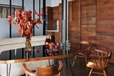 05 The dining space is done with a rich-colored wood cupboard, chairs and a chic table with a black glass top