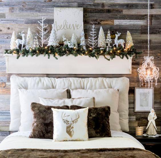 a headboard display with deer, shiny Christmas trees, a fir garland and lights