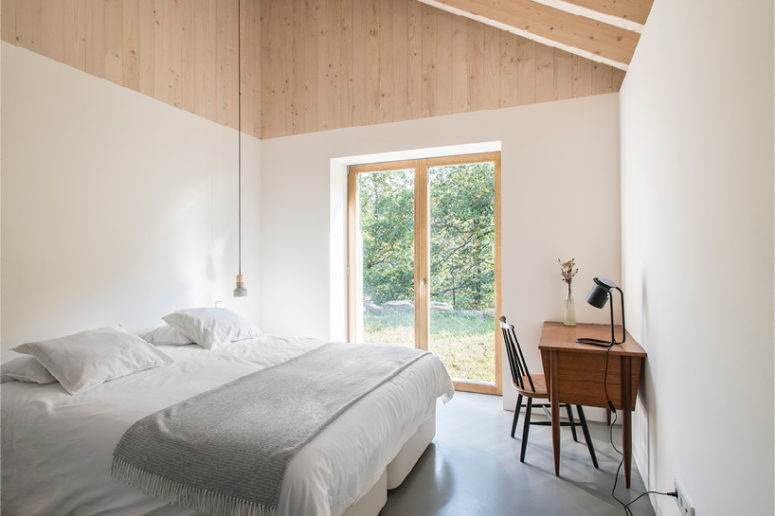 The bedroom looks very natural, there's only a bed, a vintage desk int he corner and a window with an entrance to the garden