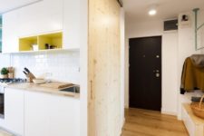 06 The entryway features some colroful hangers, a storage unit and a wooden wall