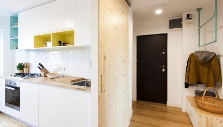 The entryway features some colroful hangers, a storage unit and a wooden wall