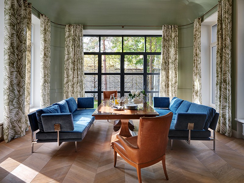 A separate dining room with a large table and two upholstered sofas is filled with light