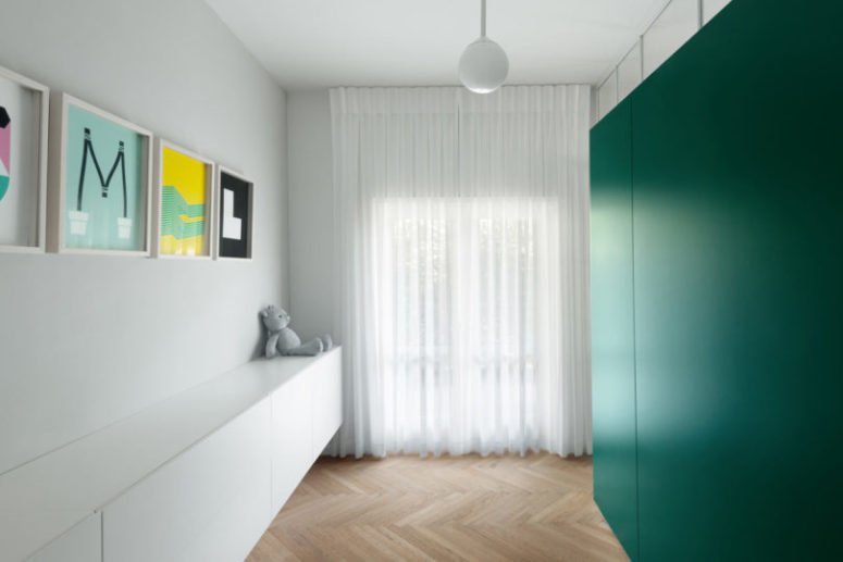 Behind the green cube there's a playing space for kids with a long storage unit with toys