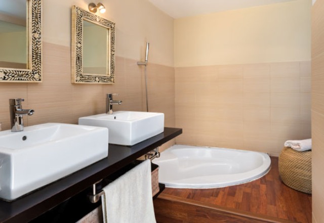 sunken bathtub in a bathroom One of the bathroom features a sunken bathtub, a double vanity with sinks and a jute ottoman