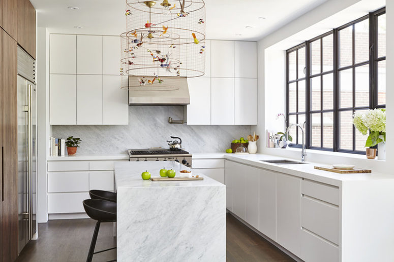 The kitchen is done with sleek white cabinets, a wooden wall with built in appliances and marble countertops The kitchen is done with sleek white cabinets, a wooden wall with built-in appliances and marble countertops