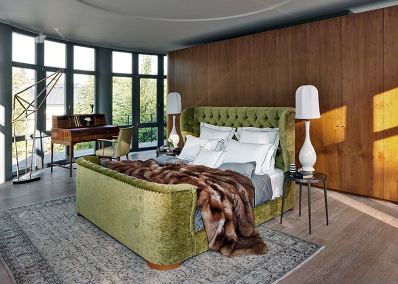 The master bedroom is done with a sleek wood storage, an upholstered velvet bed and a vintage desk