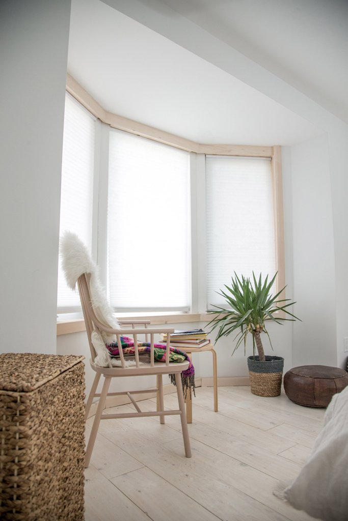 The master bedroom shows off a window of a unique shape and some modern furniture