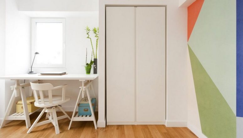 The workspace is done with a white trestle table and a sleek storage unit