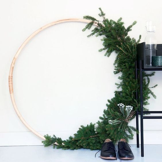an oversized wreath with evergreens and some berries on one side looks very modern and minimalist