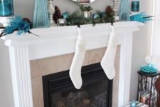 09 a glam mantel with a large mirror, blue trees, ornaments and candle holders and pinecones
