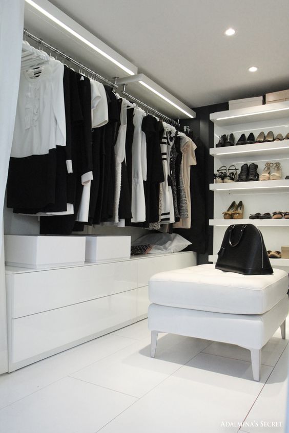 a minimalist closet in white with additional lights on the shelves to make the space look bigger