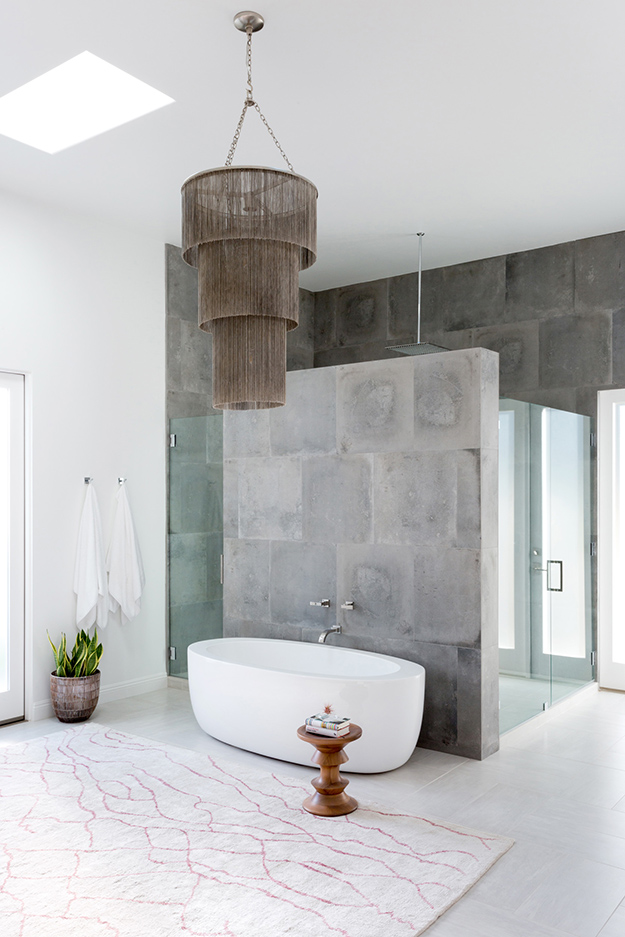 The master bathroom is done with grey stone, there's a glass shower space and a free-standing bathtub