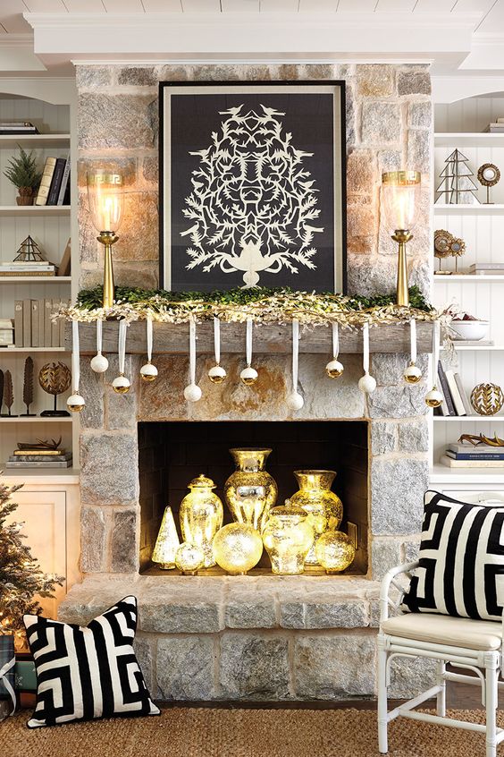 a glam fireplace and mantel display with shiny gold ornaments, a gold garland and gold vases inside