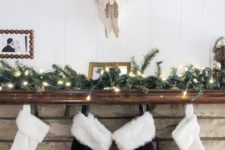 13 an evergreen garland with lights and some faux fur stockings hanging on the mantel