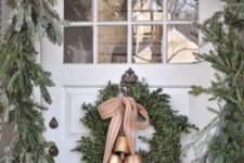 15 a lush evergreen garland to frame the font door and a wreath with bells to match the look