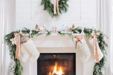 17 an evergreen wreath and garland, neutral ribbons and a snowy village display on the mantel