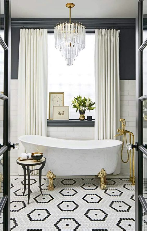 a free standing bathtub on brass clawfeet and a crystal chandelier over it