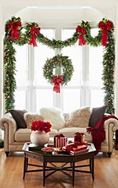 a lush evergreen garland with pinecones and lights and a matching wreath with red ribbons