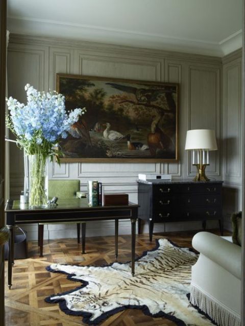 a vintage-inspired home office with paneled walls and a gorgeous painting