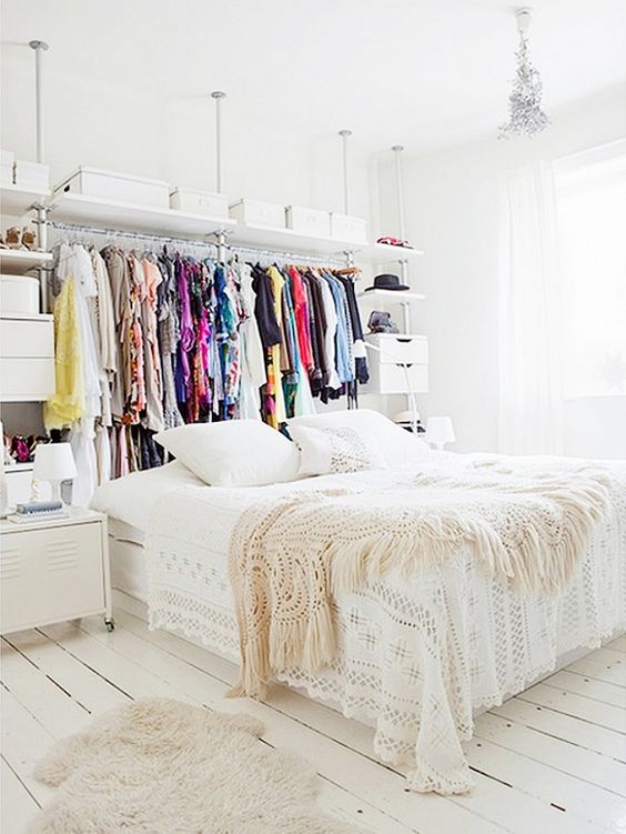 a makeshift closet placed right behind the bed looks like a creative headboard