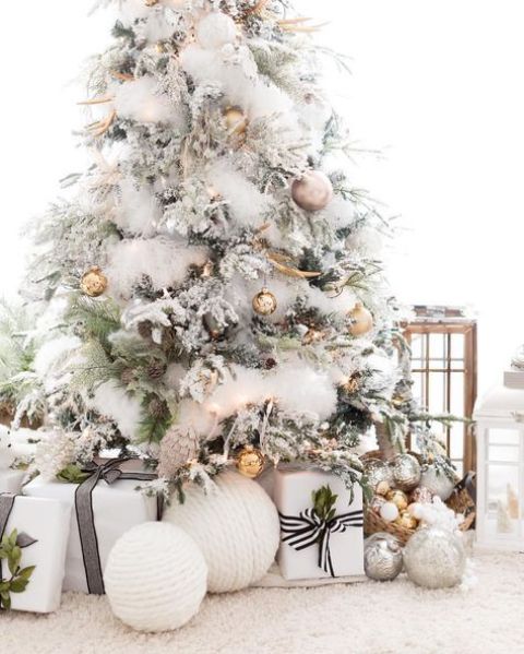 a gorgeous flocked Christmas tree with metallic ornaments of various shades and pinecones