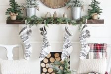 23 black and white stockings, snowy evergreen trees, an evergreen garland and a wooden Christmas clock