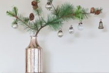 24 a pine branch with pinecones and some vintage ornaments in a single stem vase