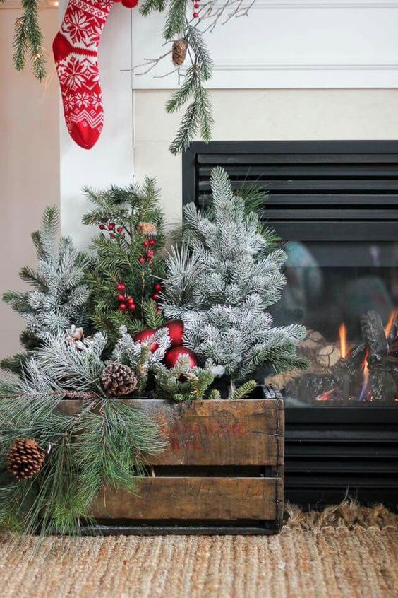 a stained crate with faux evergreens, snowy and usual ones, pinecones, berries and red ornaments