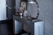 01 The entryway is industrial, with raw concrete walls and a metal console table, a crystal chandelier and a creative lamp add glam