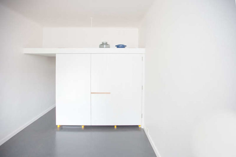 The kitchen piece can be completely closed with white doors to make it invisible in the interior and there's storage space on its top