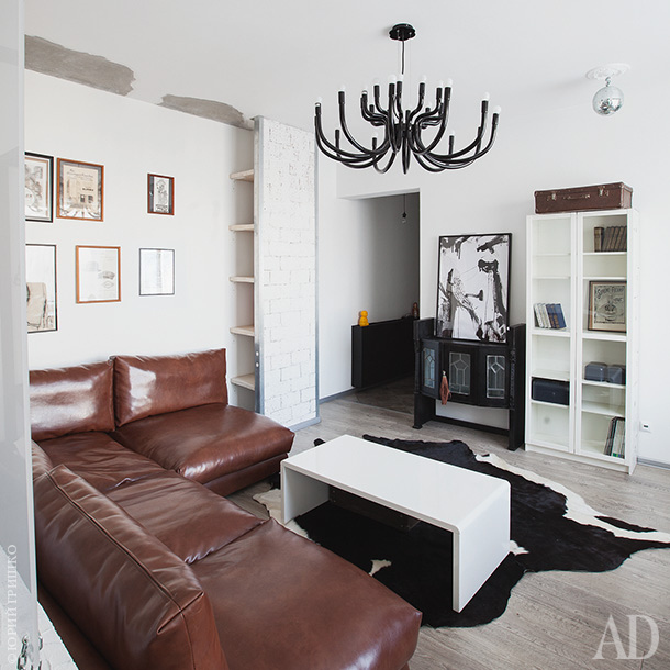 The living room features a leather sofa, a glass sideboard, there are some black touches that make the space more eye-catching