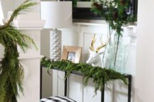 02 some evergreens, pinecones, a deer head and plaid poufs under the console for a modern natural look